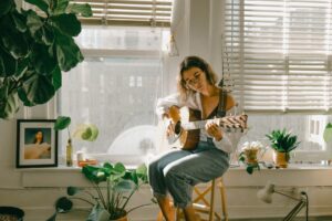 young girl with guitar in front of window