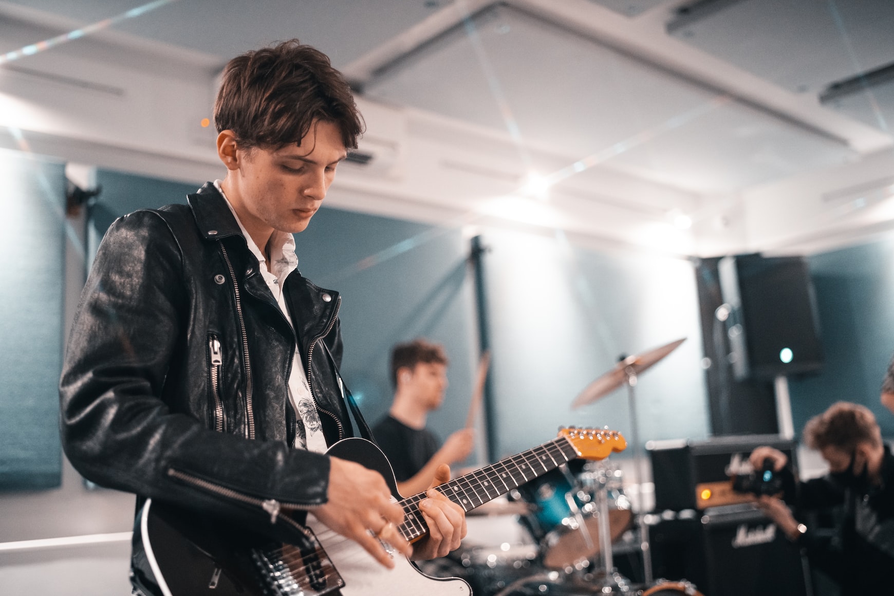 Young man with electric guitar band in background