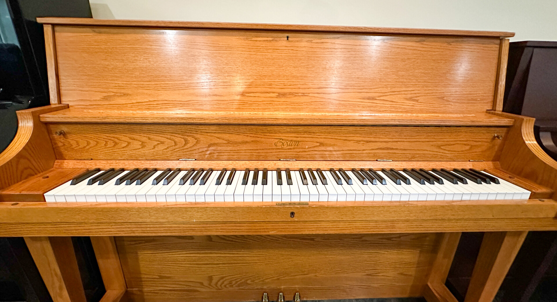 Boston UP-118 upright piano in oak finish, highlighting its classic design and well-maintained keys.