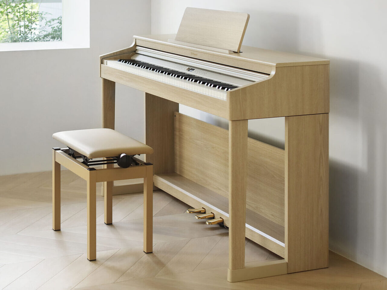 Light-wood Roland digital piano and matching bench in a bright, minimalist room with a large window.