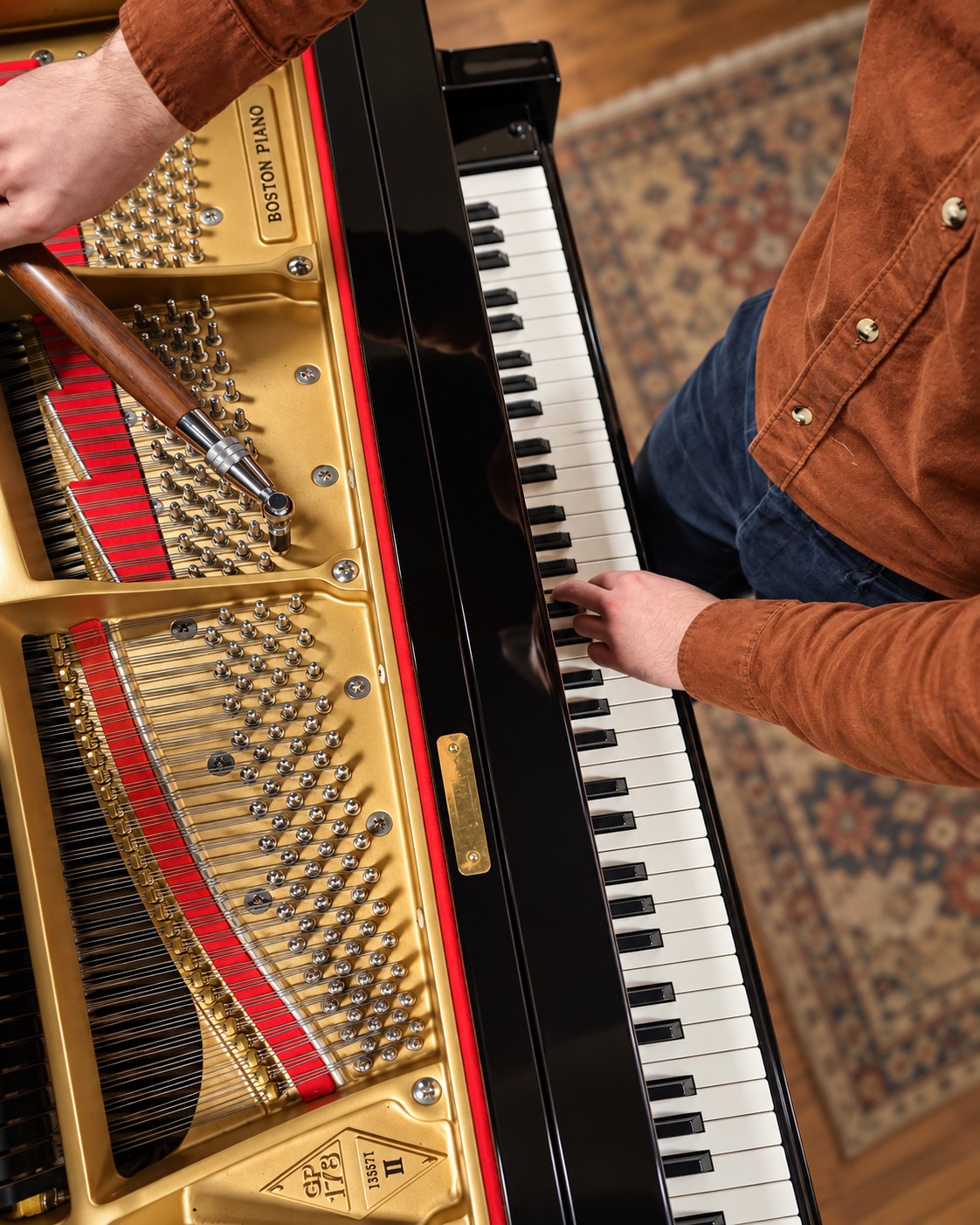 Miller Piano Specialists technician tuning a grand piano while checking notes at the keyboard.